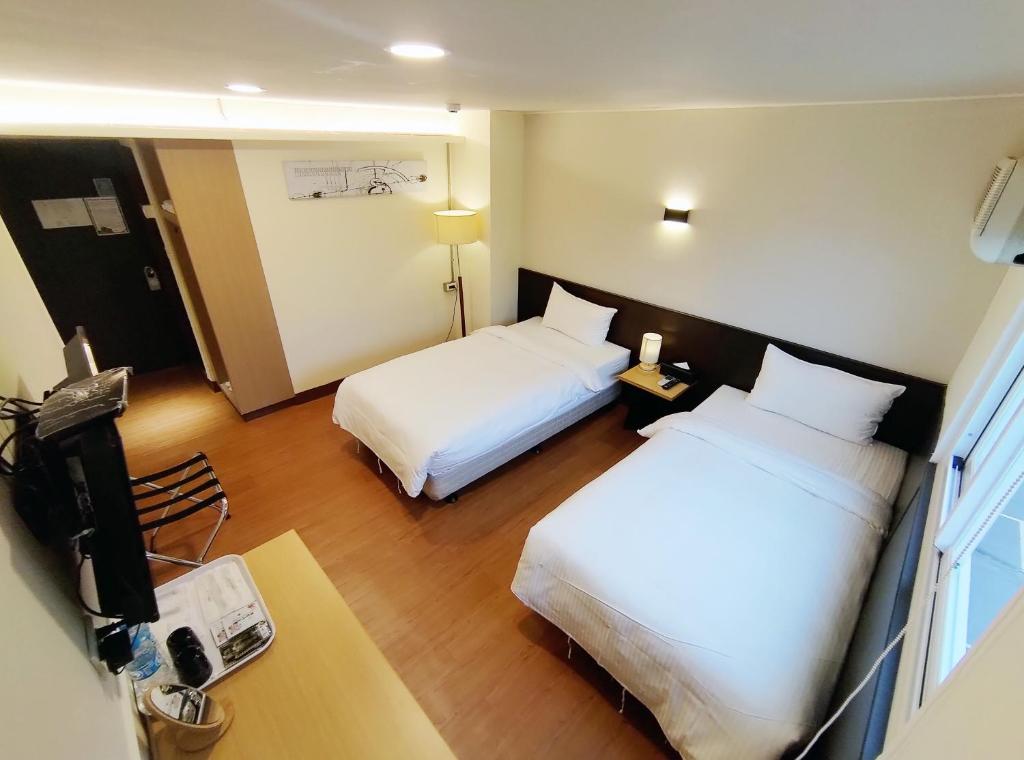 Habitación de hotel con 2 camas y escritorio en 富裕商旅 RICH-hotel, en Taitung