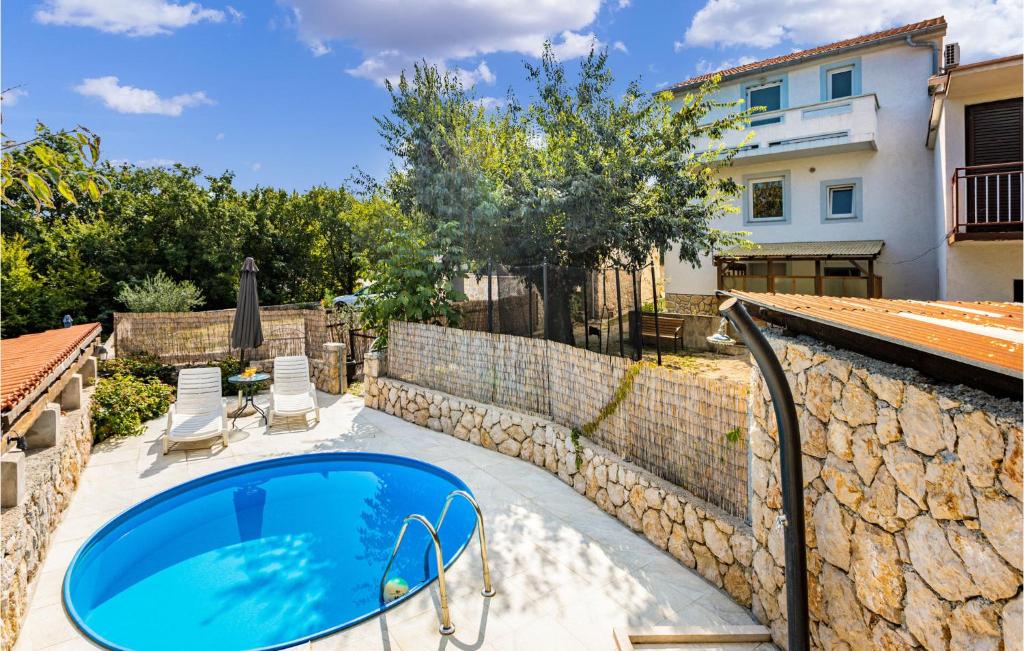 a pool in a backyard with a stone wall at Gorgeous Home In Krk With House A Panoramic View in Risika
