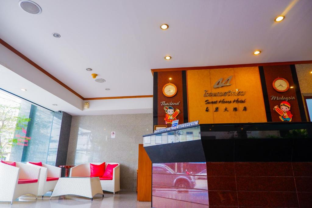 a lobby with white chairs and a counter with a sign at Sweet Home Hotel Betong in Betong