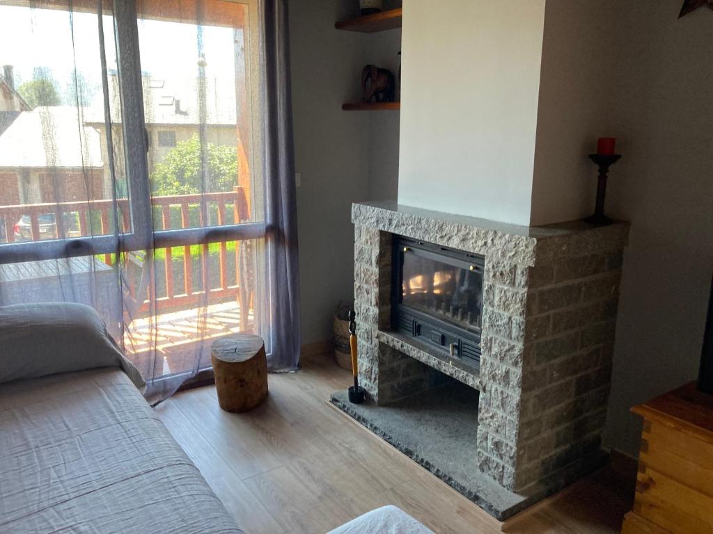 a living room with a stone fireplace with a window at Casita Planes Surroca in Bourg-Madame