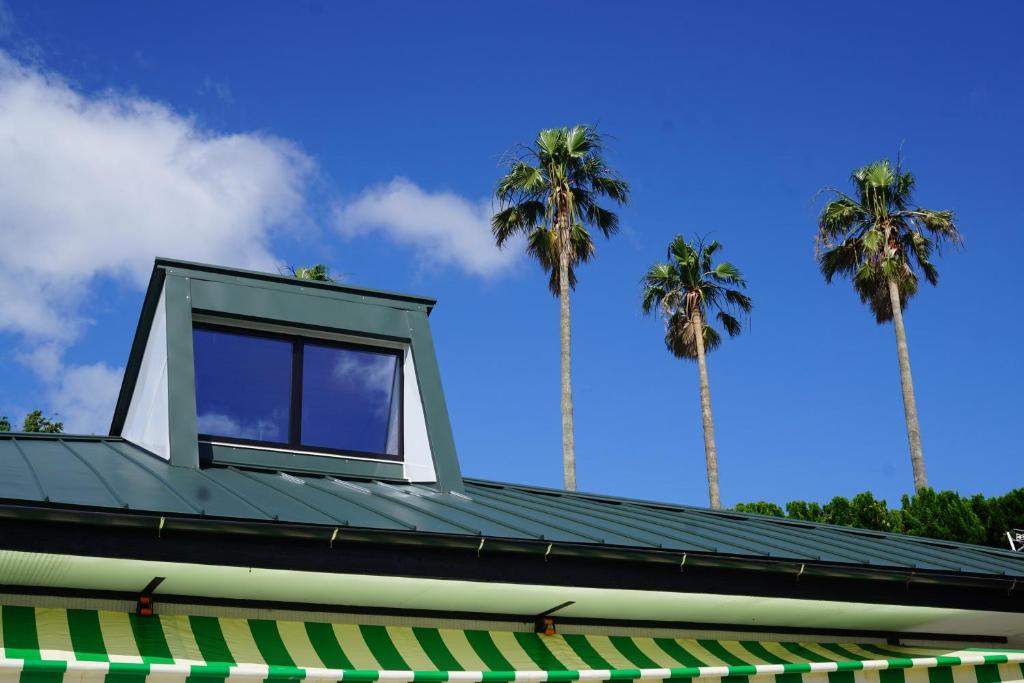 a house on top of a building with palm trees at STAY CHILL in Mitsugoe