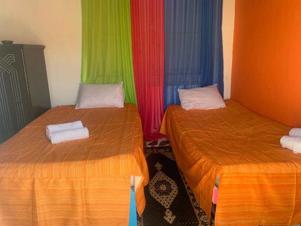 two beds with colored curtains in a room at Nubian Farm Aswan in Aswan