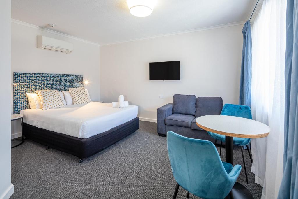 a bedroom with a bed and a table and a chair at Batemans Bay Lodge in Batemans Bay