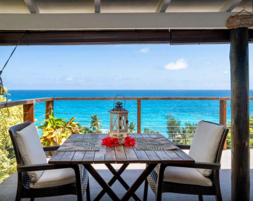 einen Holztisch mit Stühlen auf einem Balkon mit Meerblick in der Unterkunft Vi Miles Lodge in Mahé