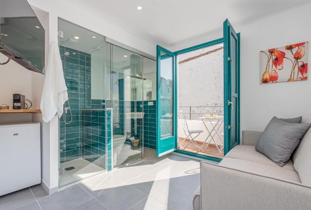 a bathroom with a glass shower and a couch at Habitacions Bellaire Cadaqués in Cadaqués