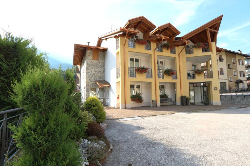 un gran edificio amarillo con cajas de flores. en Hotel Garni Sottobosco, en Dimaro