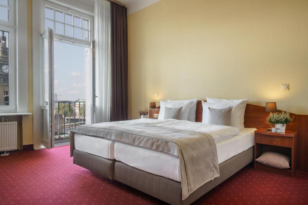 a bedroom with a large bed and a large window at Novum Hotel Kronprinz Hamburg Hauptbahnhof in Hamburg