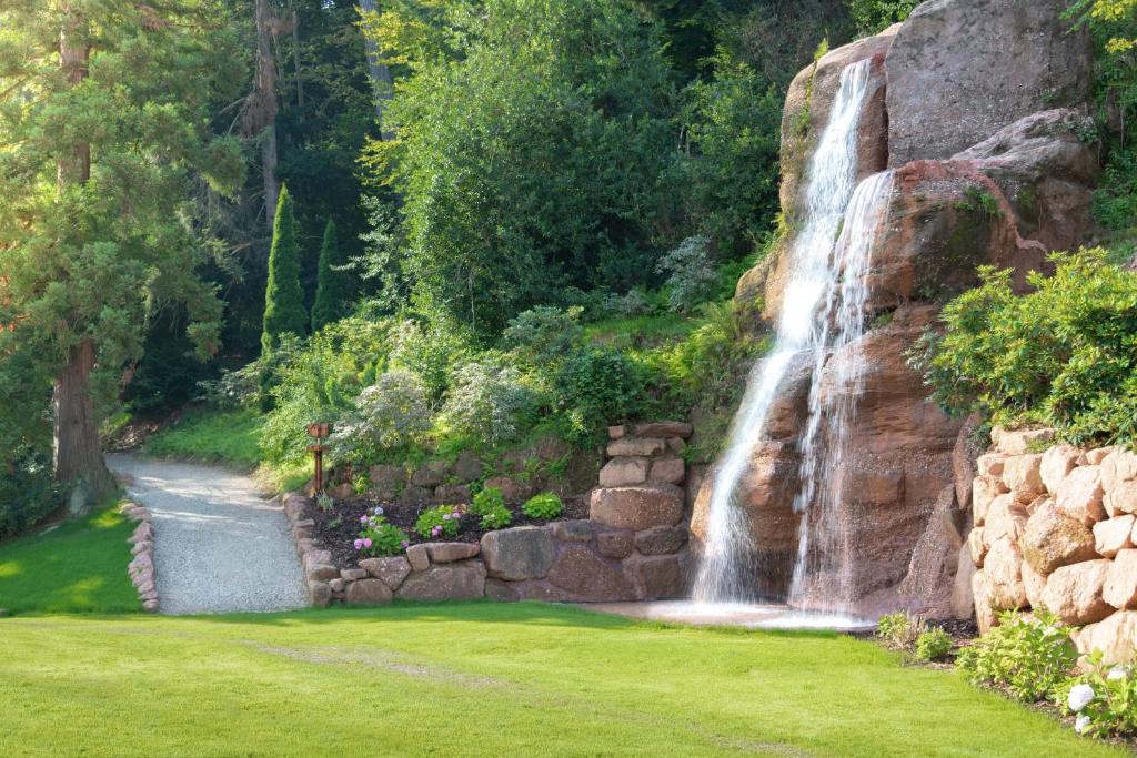 a waterfall in a park with a green lawn at 6717 Nature Hôtel &amp; Spa Le Clos des Délices in Ottrott