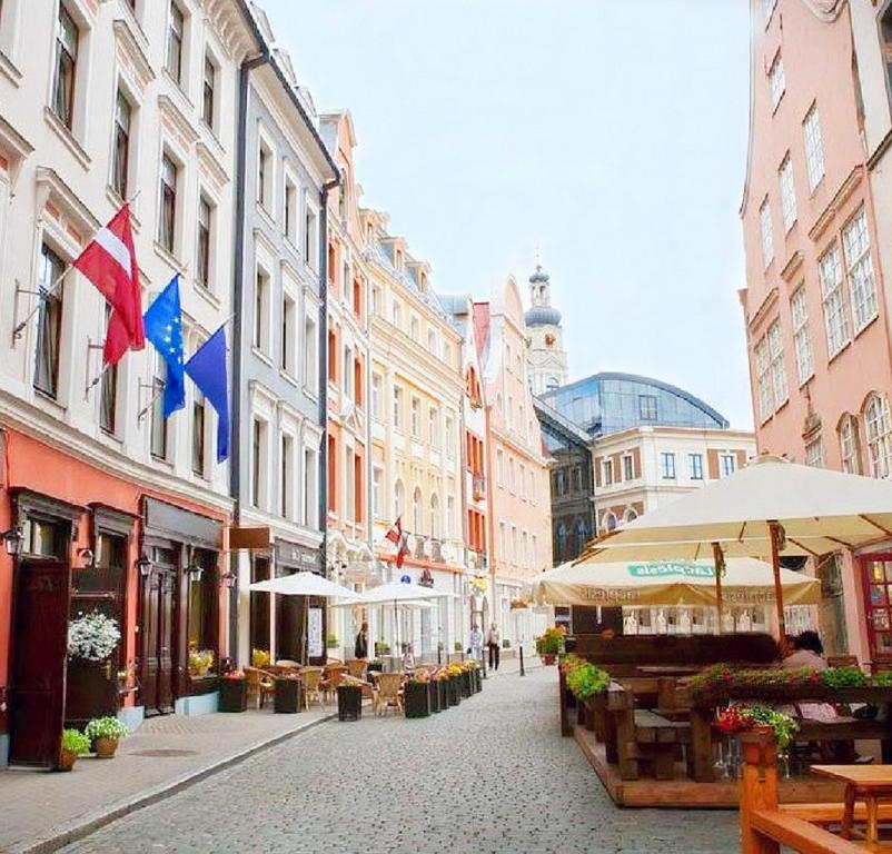 a street with buildings and umbrellas in a city at Rija Domus Hotel in Riga