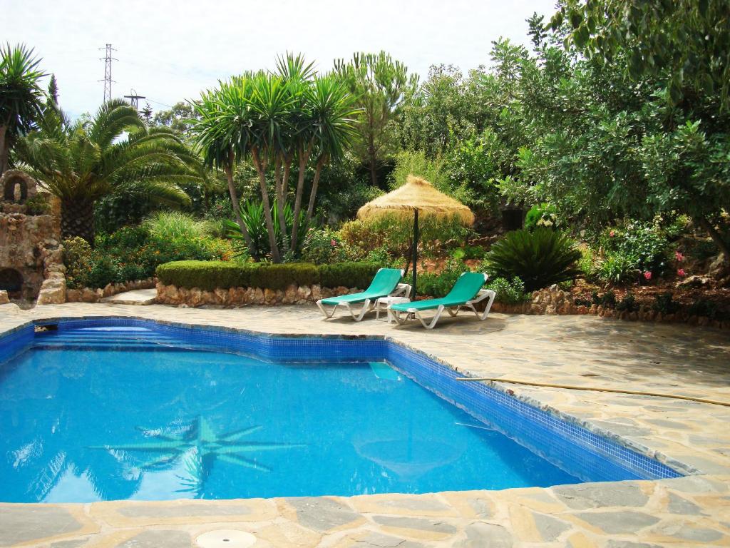 basen z 2 krzesłami i parasolem w obiekcie Tu Villa Rural Cabaña 2 Dormitorios w mieście Alhaurín el Grande