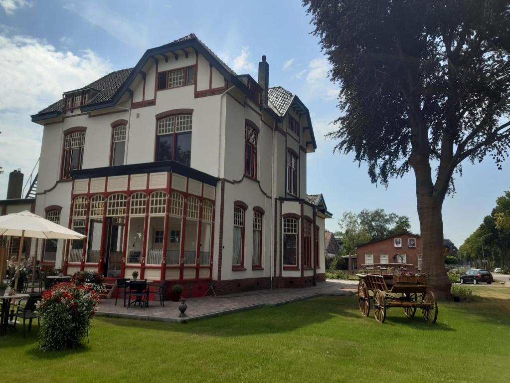 ein großes weißes Haus mit einem Tisch im Hof in der Unterkunft B&B Villa de Beuk in Stadskanaal