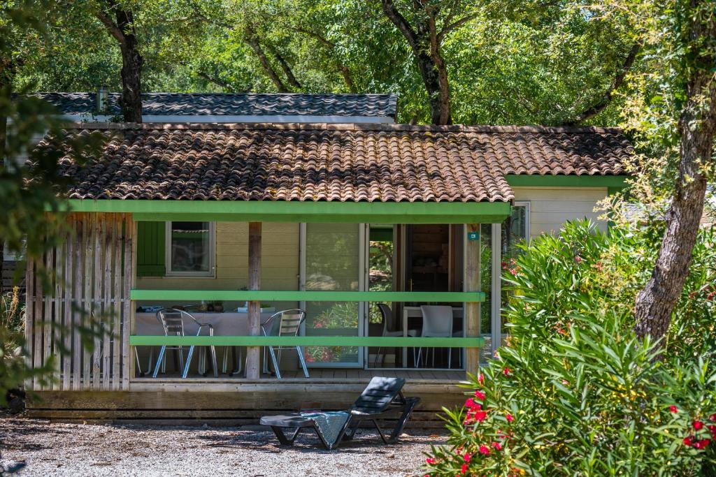 Ce cottage verdoyant dispose d&#39;une cour avec une table et des chaises. dans l&#39;établissement Camping Le Bois Fleuri, à Argelès-sur-Mer