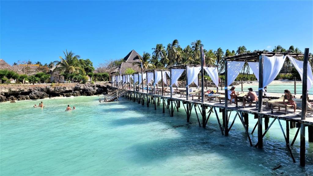 a pier with people in the water at a beach at Reef & Beach Resort - Spa Jambiani in Jambiani