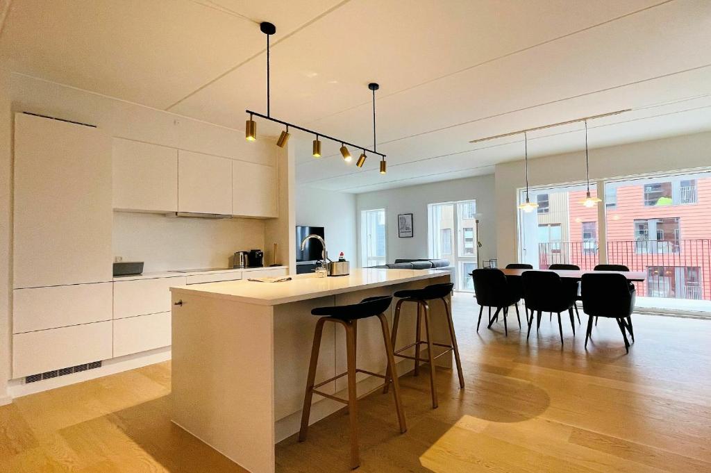 una cucina con armadi bianchi e un bar con sedie nere di ApartmentInCopenhagen Apartment 1463 a Copenaghen