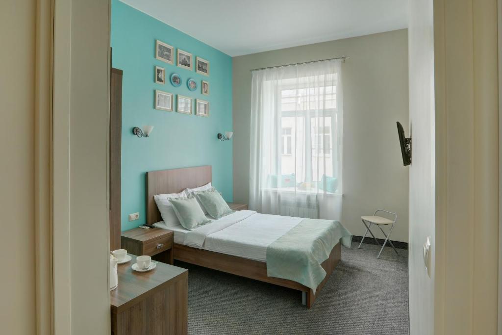 a blue bedroom with a bed and a window at Algen on Goncharnya in Saint Petersburg