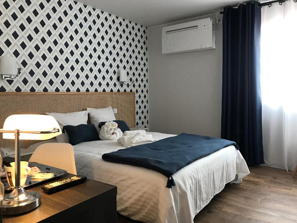 a bedroom with a large bed and a table with a table at Hôtel Le Glacier in Villeneuve-sur-Lot