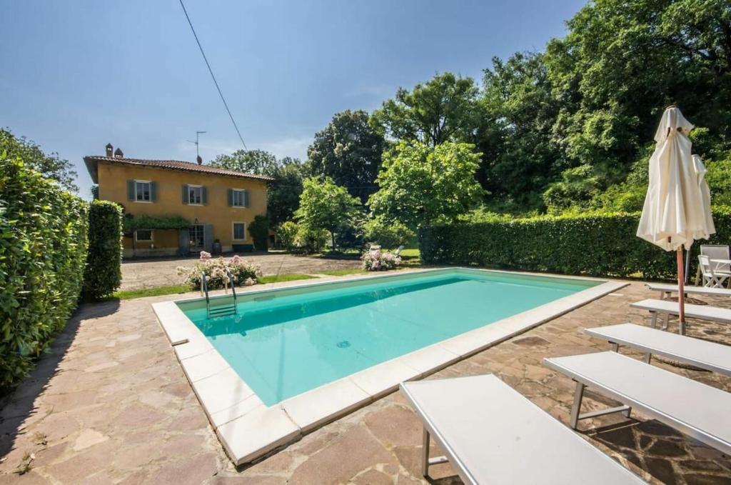 a swimming pool with an umbrella and a house at Villa Iole in Bucine