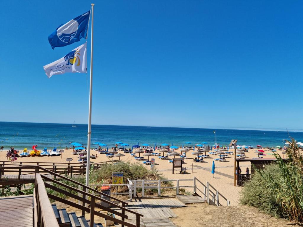 een strand met twee vlaggen en stoelen en de oceaan bij Velamar Praia 411 - 300m da praia in Albufeira
