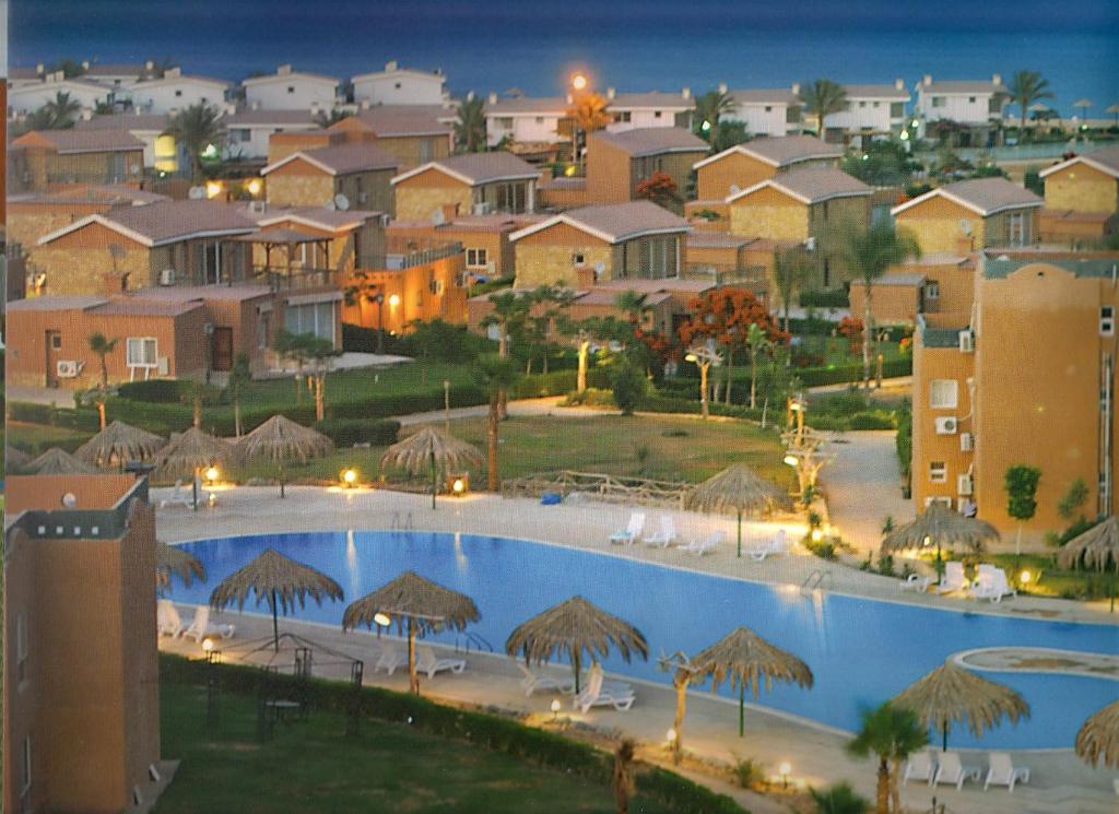 a large swimming pool with umbrellas and a resort at Marina Wadi Degla A Ground Chalet Near to the Beach in Ain Sokhna in Ain Sokhna