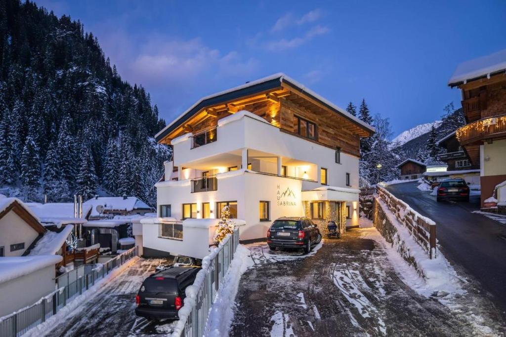 a house with cars parked outside of it in the snow at Haus Sabrina Hexenkopf in See