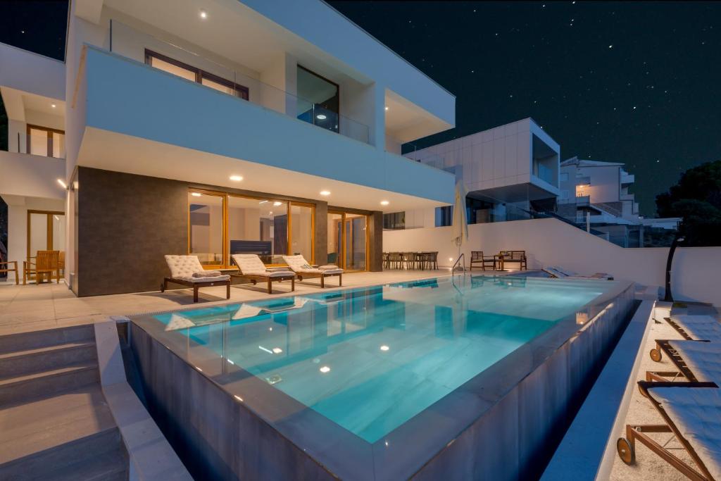 ein Schwimmbad im Hinterhof eines Hauses nachts in der Unterkunft Luxury Villa Hedone in Baška Voda