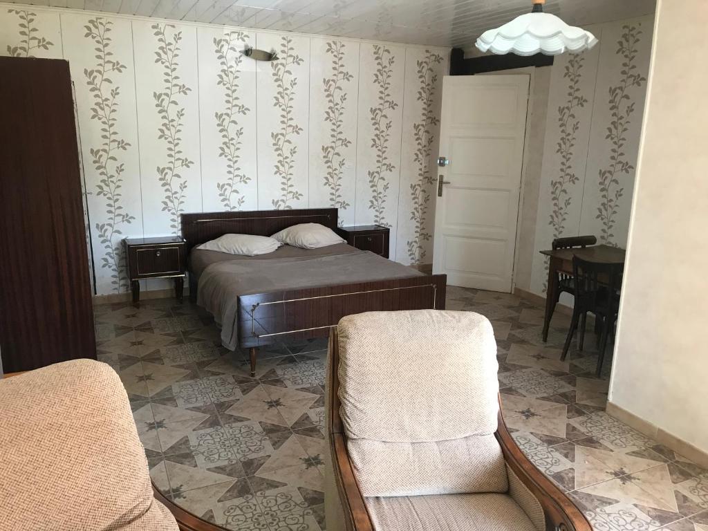 a bedroom with a bed and a chair and a table at Métris de la place in Corre