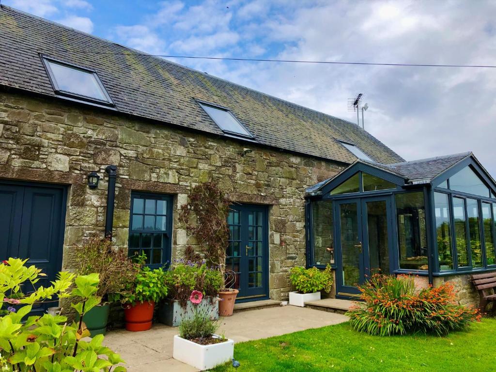 una antigua casa de piedra con un salón acristalado en un patio en Trossachs Barn & Cabin en Port of Menteith