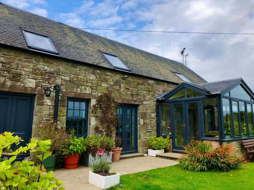 an old stone house with a conservatory in a yard at Trossachs Barn & Cabin in Port of Menteith