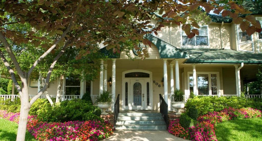 een wit huis met bloemen ervoor bij The Sanford House Inn & Spa in Arlington