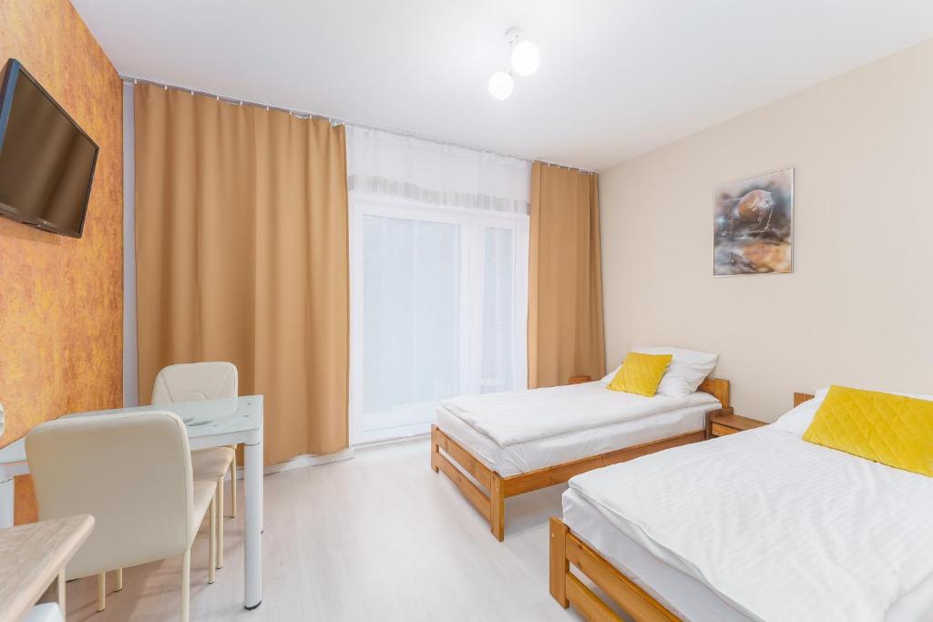 a room with two beds and a desk and a tv at APT Nadmorskie - Spokojne in Kołobrzeg