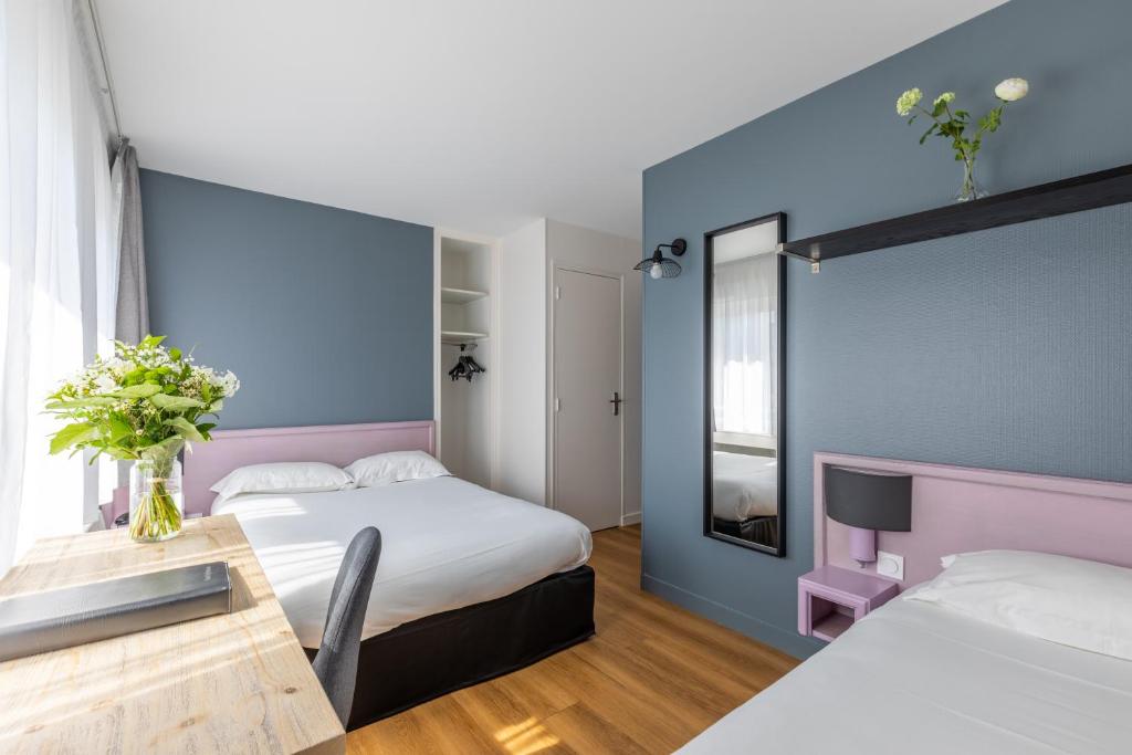 a hotel room with two beds and a table at Atlantic Hotel Rennes Centre Gare in Rennes