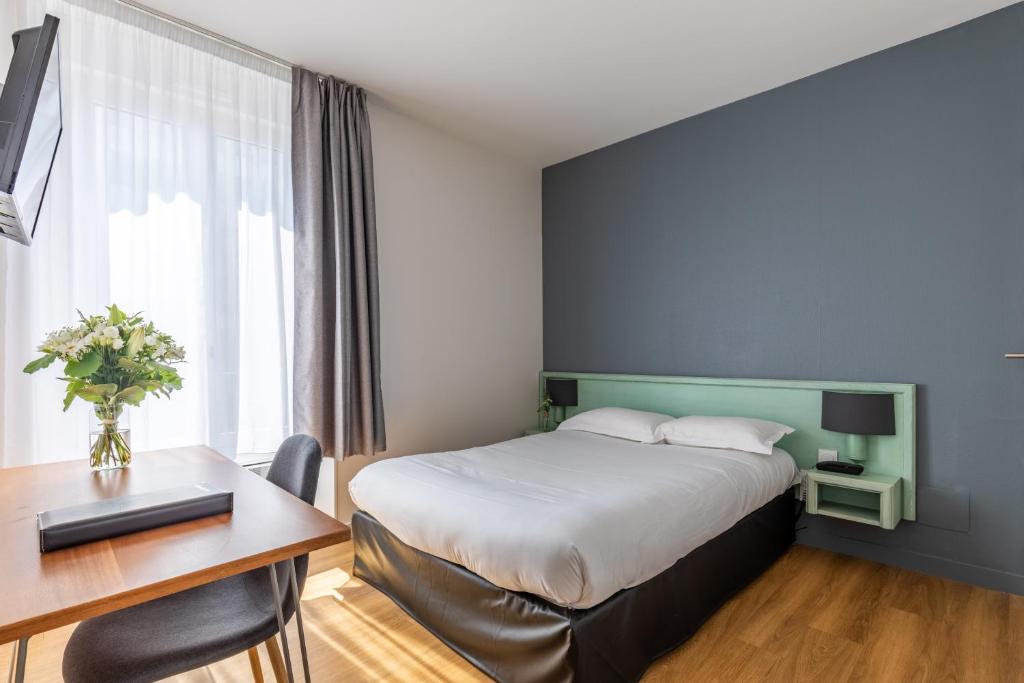 a hotel room with a bed and a desk and a desk at Atlantic Hotel Rennes Centre Gare in Rennes