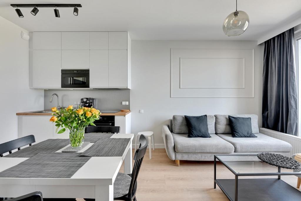 a white living room with a table and a couch at Blue Mandarin - Chlebova Apartments in Gdańsk