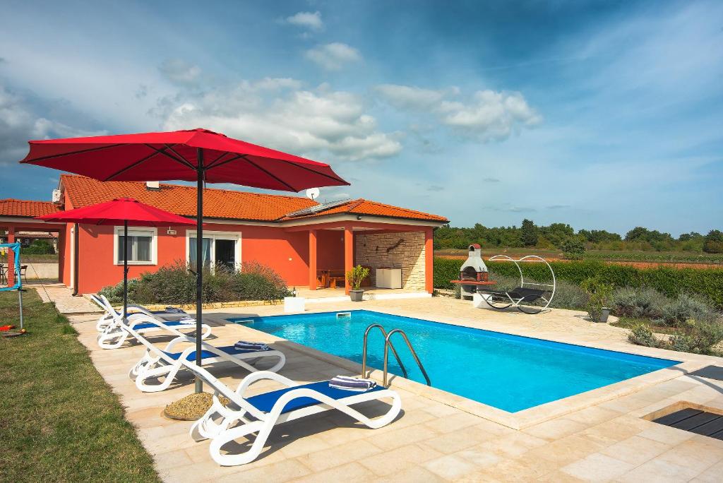 uma piscina com espreguiçadeiras e um guarda-sol em Villa Kata em Krnica