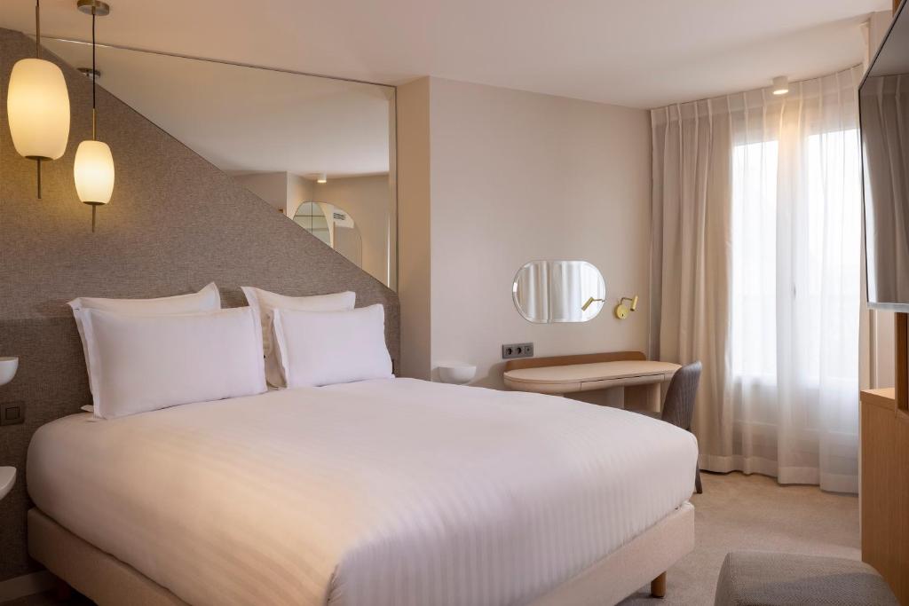 パリにあるHôtel Beigeの白い大型ベッド1台と窓が備わるホテルルームです。