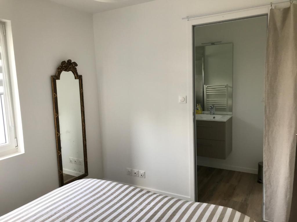 sypialnia z lustrem, łóżkiem i umywalką w obiekcie Un sejour a Cabourg w mieście Cabourg