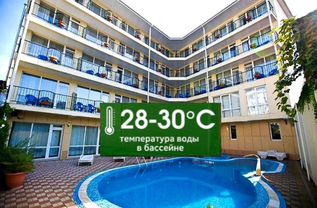 un cartel frente a un edificio con piscina en Galotel Adler Hotel, en Adler
