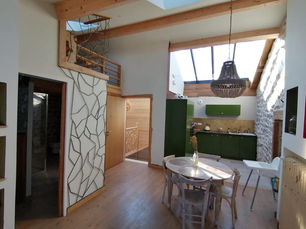 a kitchen and dining room with a table and chairs at Joubarbe Les Herbes de la Saint Jean in Saint-Bonnet-le-Froid