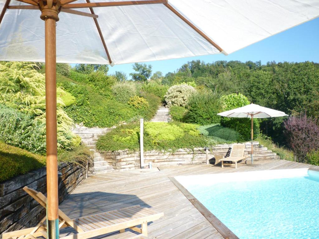 una sombrilla y sillas junto a la piscina en Les Gîtes du Lachat, en Saint-Sylvestre