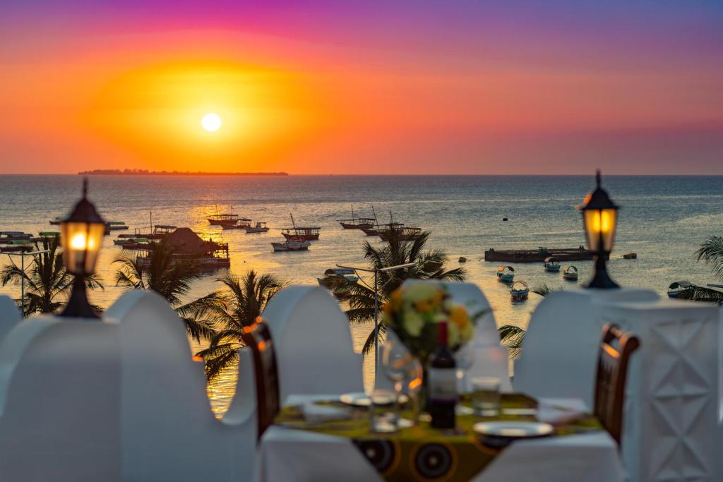 een tafel met uitzicht op het strand bij zonsondergang bij The Seyyida Hotel and Spa in Zanzibar City