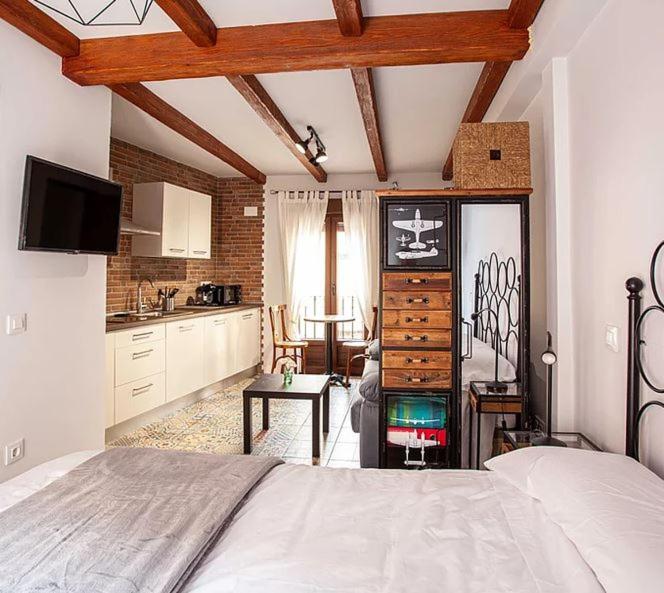 a bedroom with a large bed and a kitchen at APARTAMENTOS LA VIEJA IMPRENTA in Sigüenza