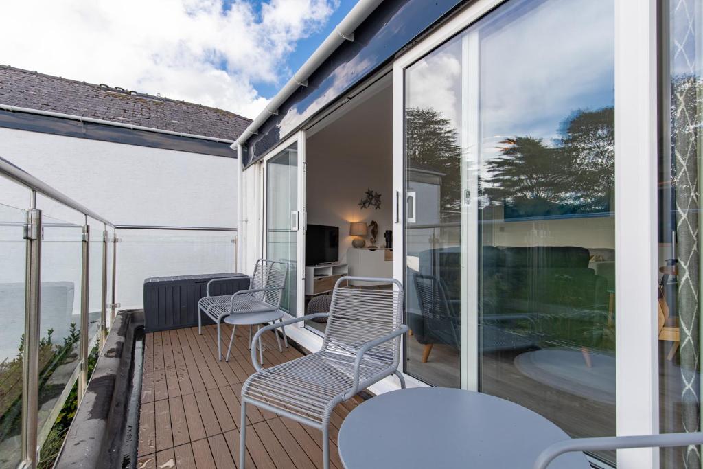 balcón con sillas, mesa y algunas ventanas en 25 Coedrath Park - Sea Views from Balcony, Short Walk to Beach, Parking, en Saundersfoot