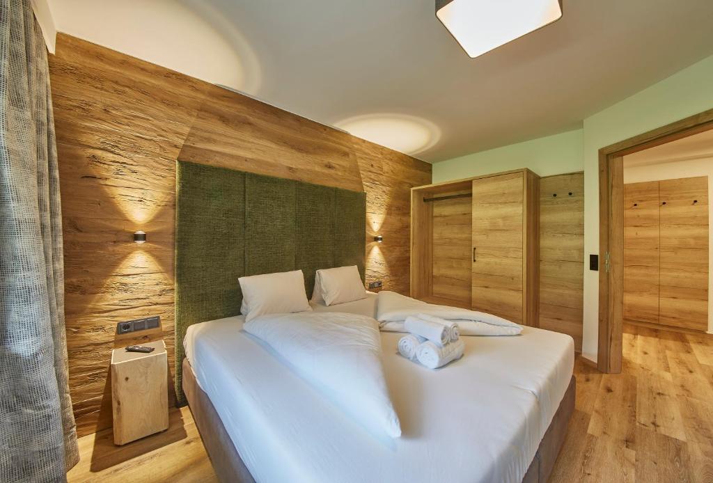 1 cama blanca grande en una habitación con paredes de madera. en Appartements Gappmaier, en Saalbach Hinterglemm