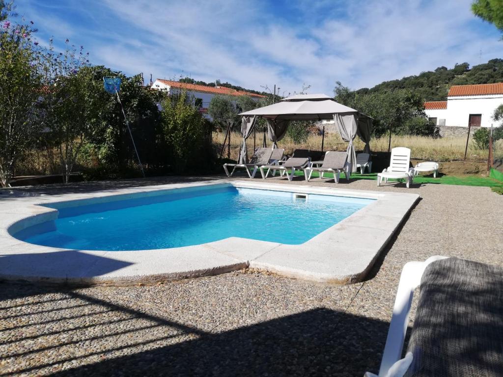 - Piscina con mesa y sombrilla en Casas Rurales Los Montes, en La Corte