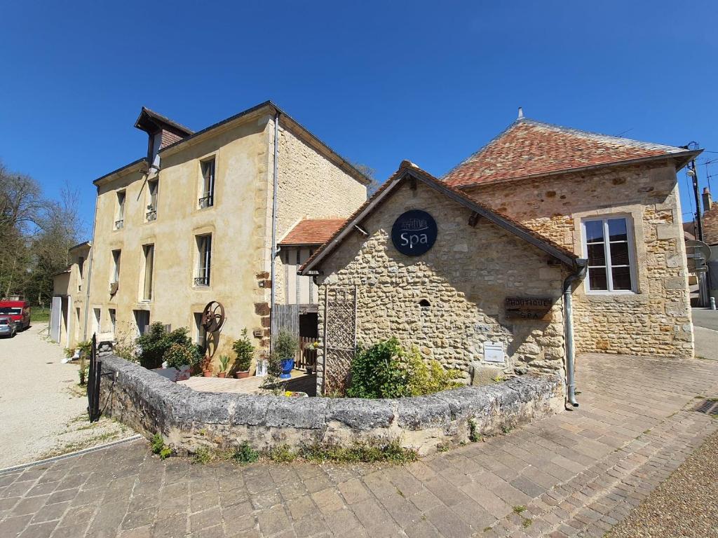 ein Steingebäude mit einer Uhr auf der Seite in der Unterkunft Gîte du Moulin de Barutel Mamers,Petite maison avec 1 chambre idéale couple,SPA et Soins sur réservation in Mamers