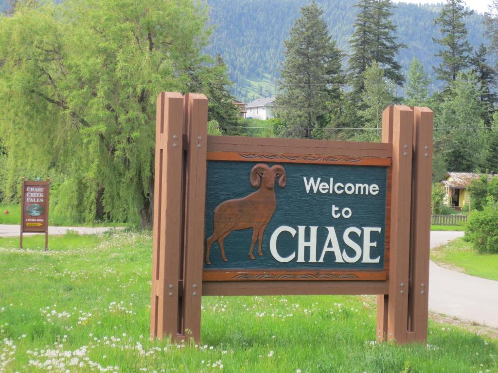 a sign on a wooden post in front of a forest at Chase Country Inn in Chase