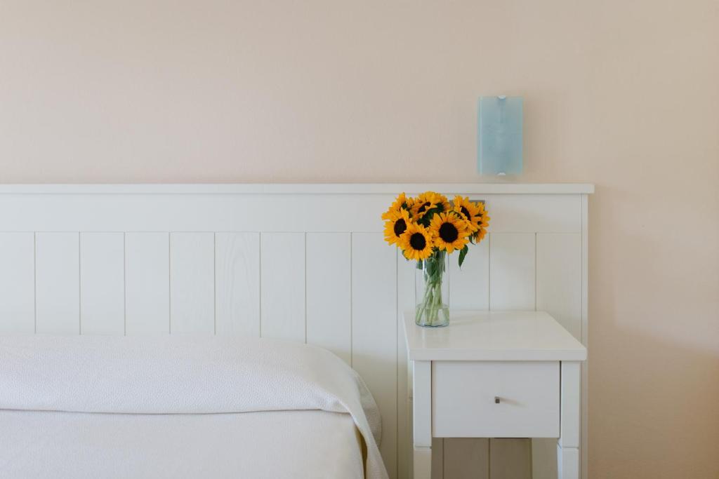 eine Vase Sonnenblumen auf einem Tisch neben einem Bett in der Unterkunft Marin Hotel in Pula