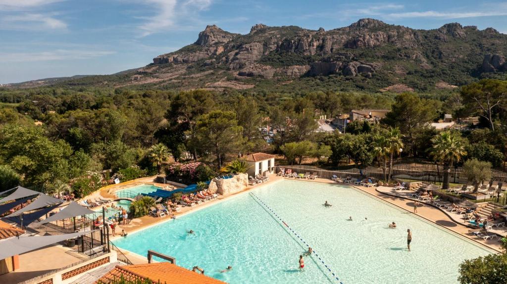 a pool at a resort with a mountain in the background at Camping RCN Domaine de la Noguière in Le Muy