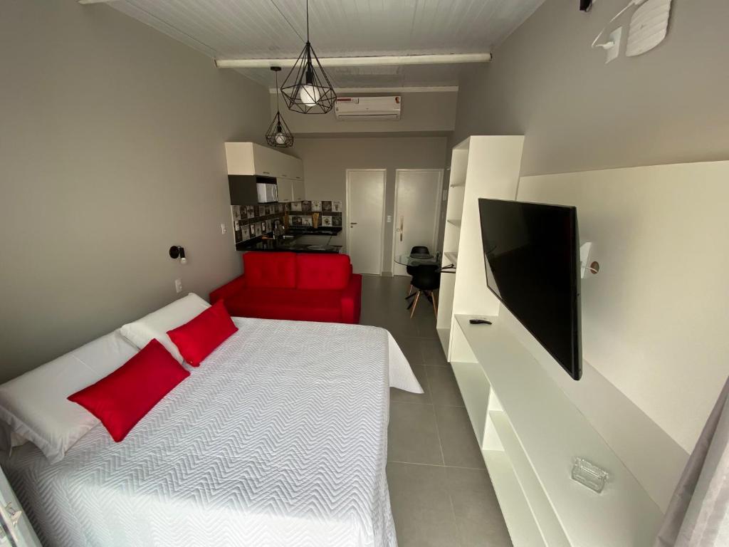 a bedroom with a white bed and a red couch at Waikiki Apartament Ipanema in Rio de Janeiro