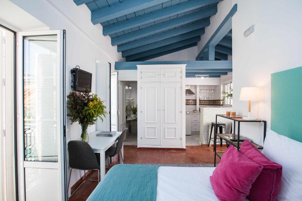 a bedroom with a bed and a table and a kitchen at Alojarte Mezquita 5 in Seville